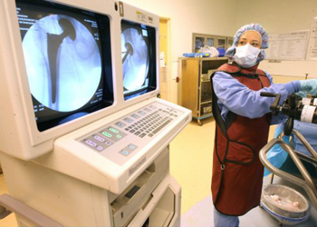 Circulating nurse Lucy Sousa stands by the Hana table while x-rays logo