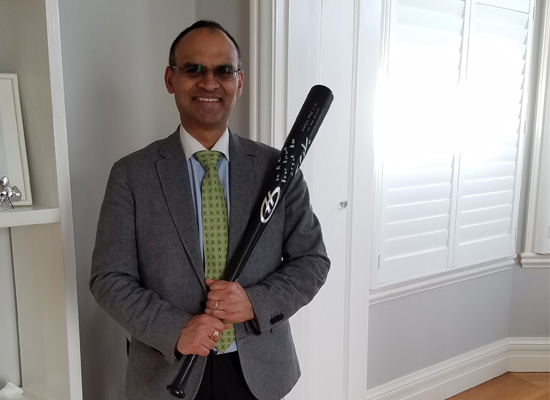 Dr. Misra holding a bat as received as a gift for taking care of a catcher from the Oakland Athletics farm system.