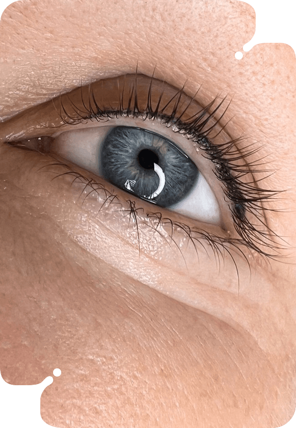 Close-up of a woman's blue eye with laminated lashes.