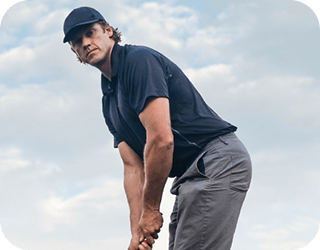 A man grips a golf club on a golf course, representing life after surgery.