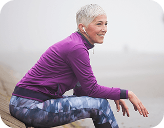 A woman on a bench with crossed legs, relaxed after knee surgery.